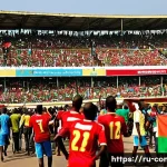 Home 19 콩고 공화국에서 인기 있는 스포츠 팀 및 선수 - A vibrant scene at a bustling football stadium in Brazzaville, Republic of Congo, featuring a divers...
